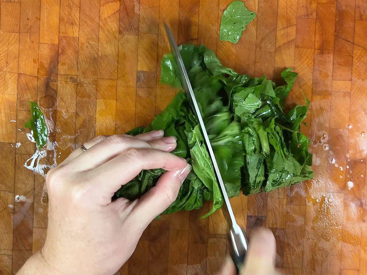 Using a sharp knife to cut the turnip green leaves into ribbons.