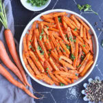 Serving dish of air fryer roasted carrots garnished with fresh parsley.