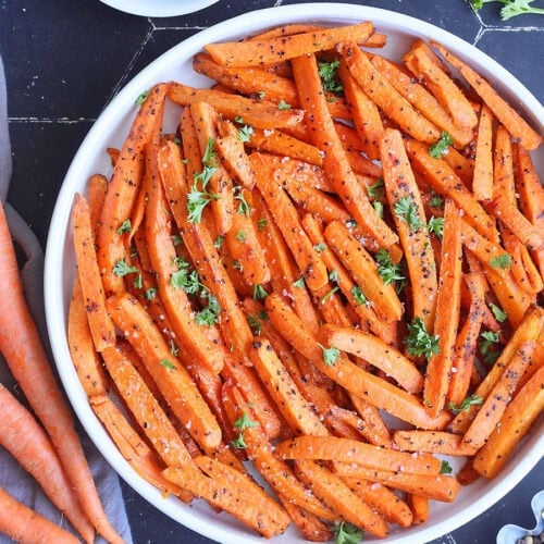 Serving dish of air fryer roasted carrots garnished with fresh parsley.