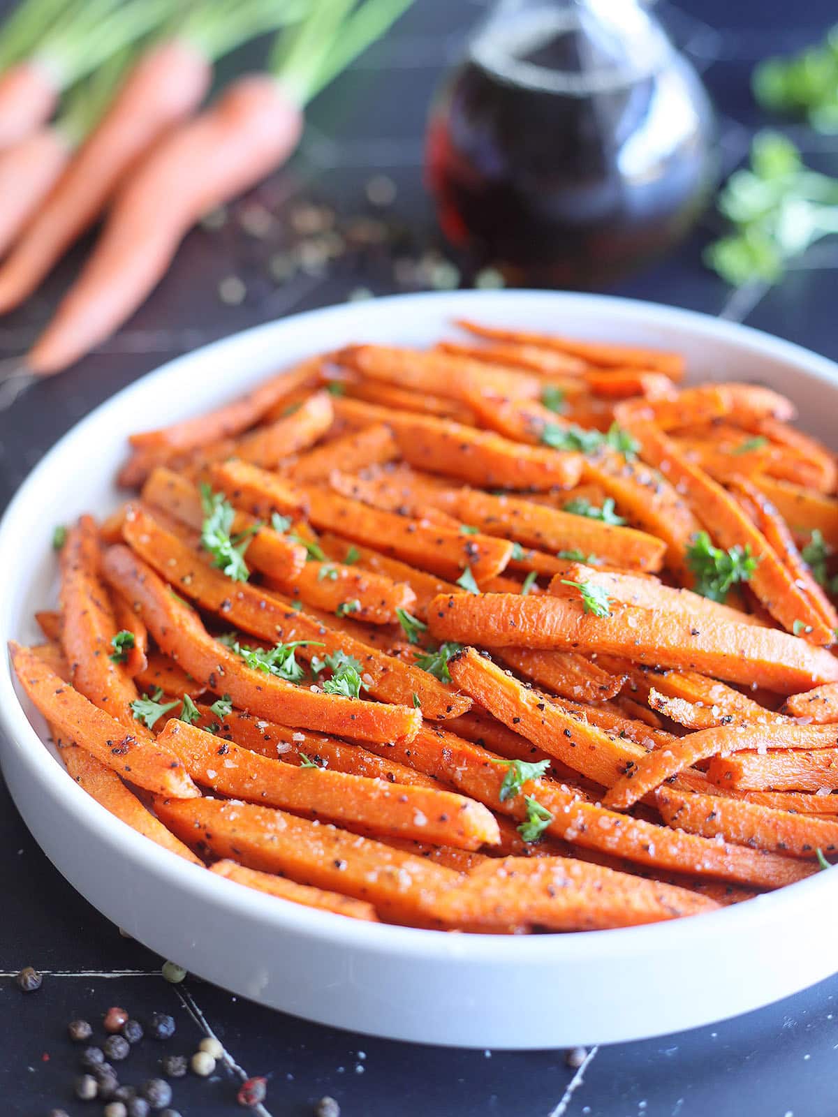 Serving dish of air fryer roasted carrots garnished with fresh parsley.