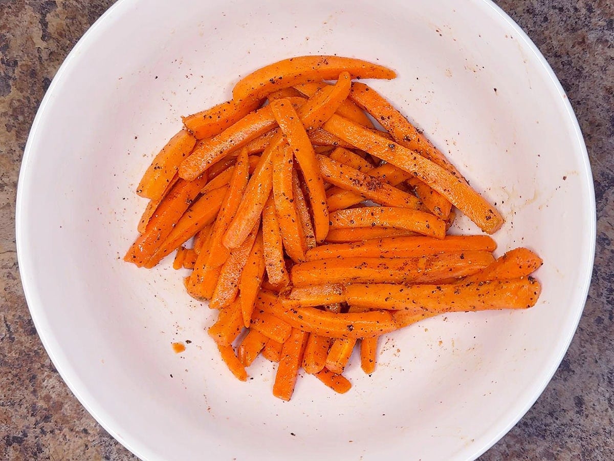 Seasoning the carrots with olive oil and spices.
