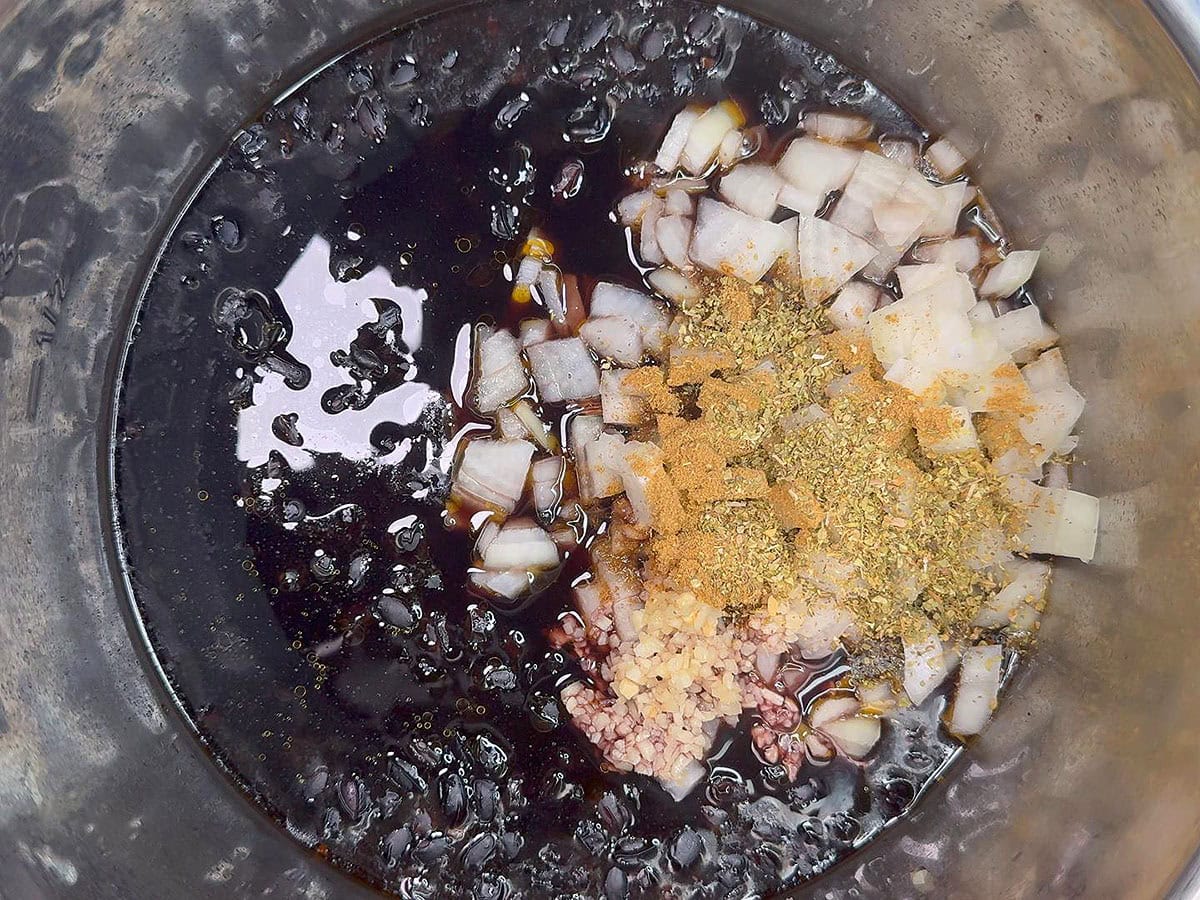Adding onions, garlic, and spices to the softened black beans.