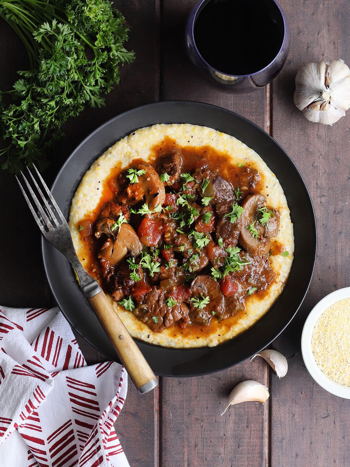 Bowl of grillades and grits garnished with chopped fresh parsley.