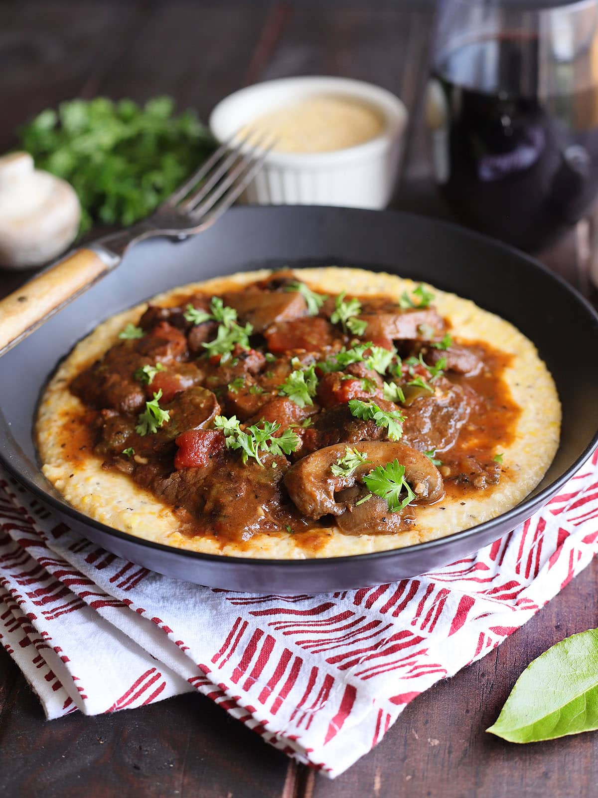 Bowl of grillades and grits garnished with chopped fresh parsley.