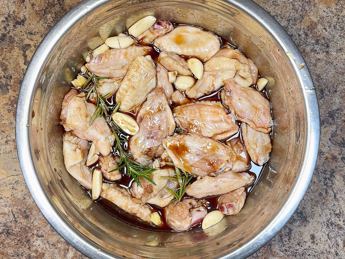 Chicken wings marinating in a large mixing bowl.