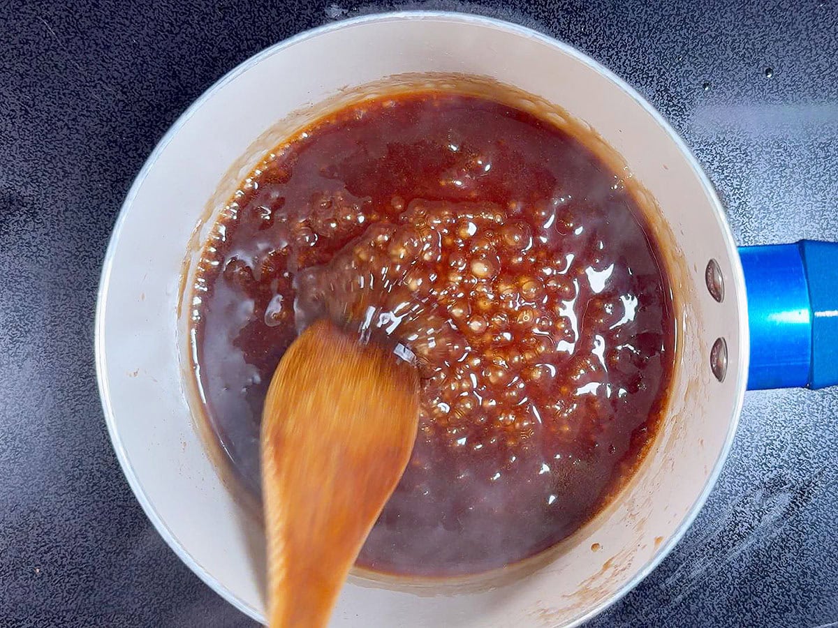 Boiling the reserved honey garlic sauce in a saucepan until thickened.