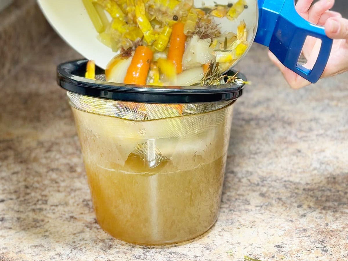 Straining the shrimp stock through a mesh sieve.
