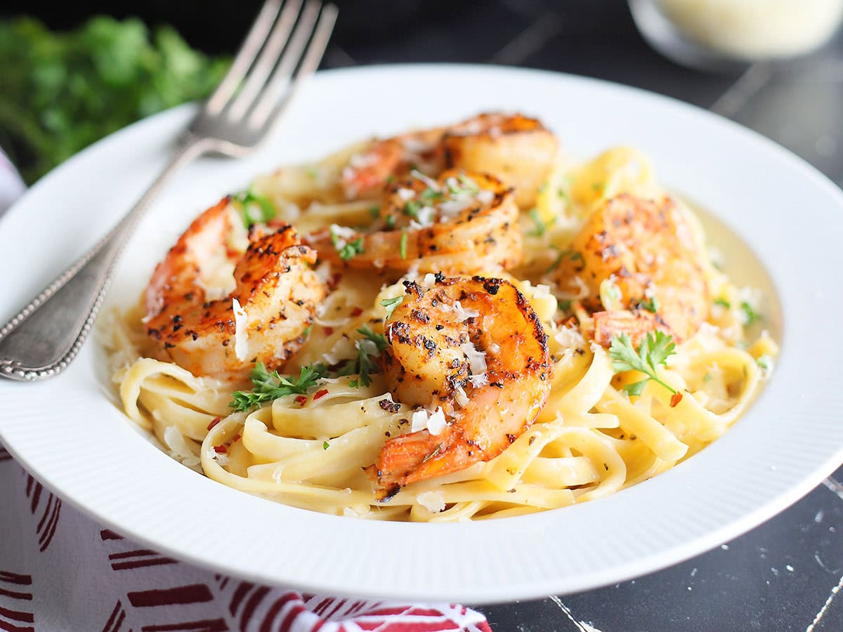 Blackened shrimp on a bed of fettuccine noodles coated in alfredo sauce.