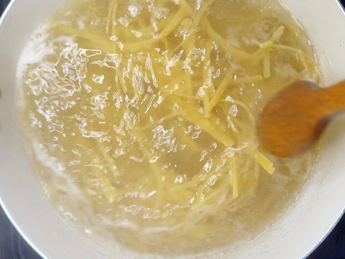 Cooking fettuccine noodles in boiling water.