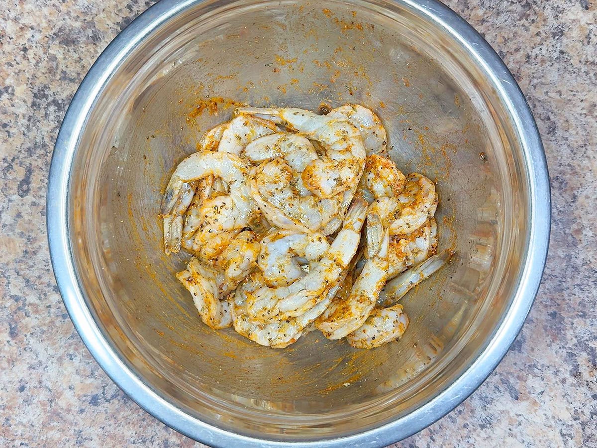 Seasoned raw shrimp in a mixing bowl.