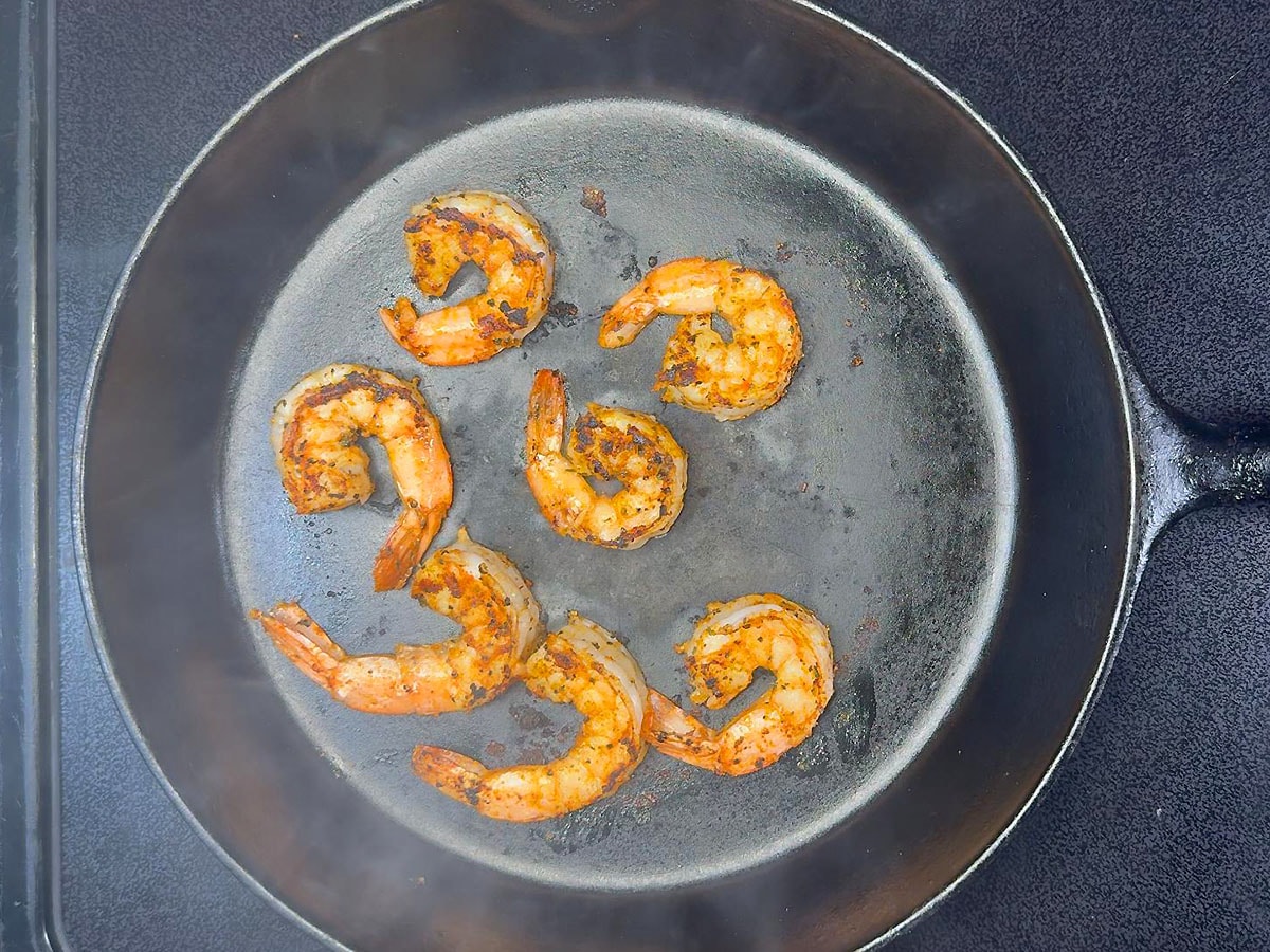 Cooking seasoned shrimp in a cast iron skillet.