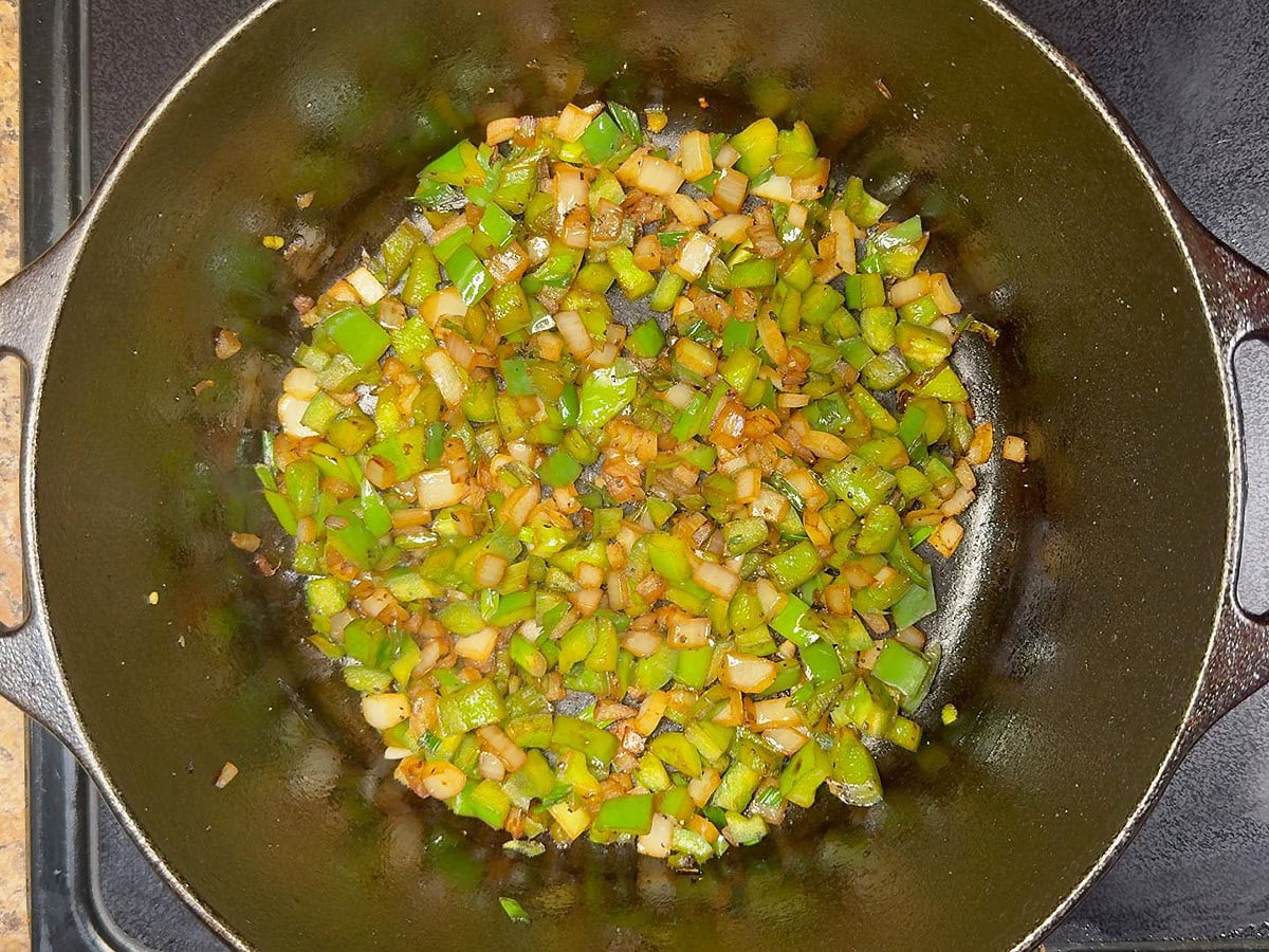 Sauteed onions and green bell peppers in a cast iron Dutch oven.
