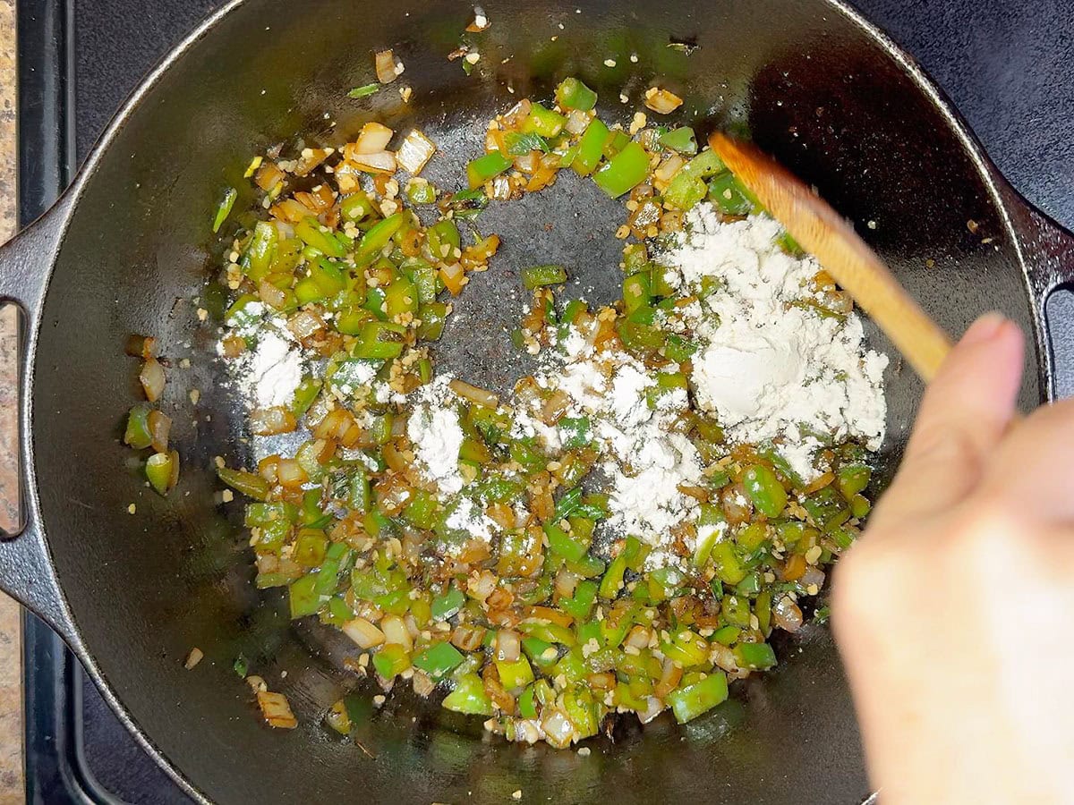 Adding flour to the sauteed vegetables.