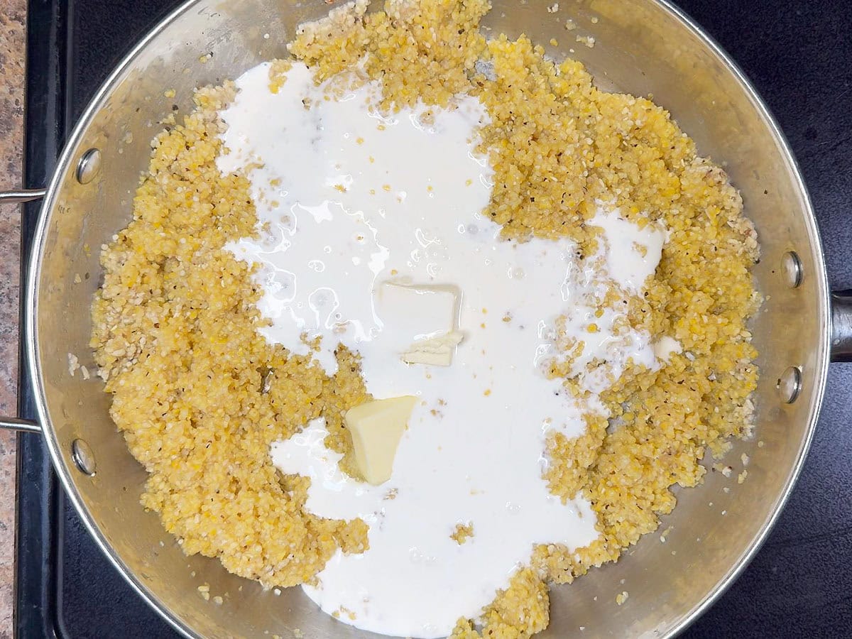 Cooked grits in a large saucepan with butter and heavy cream added.