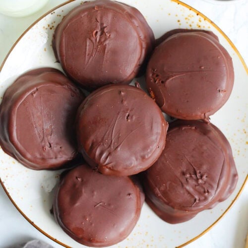Plate of moonpies surrounded by a bowl of chocolate chips and bottles of milk.