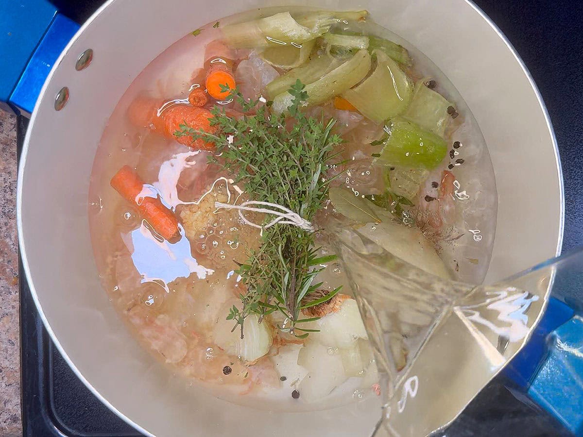 Pouring water over the shrimp shells and aromatics.