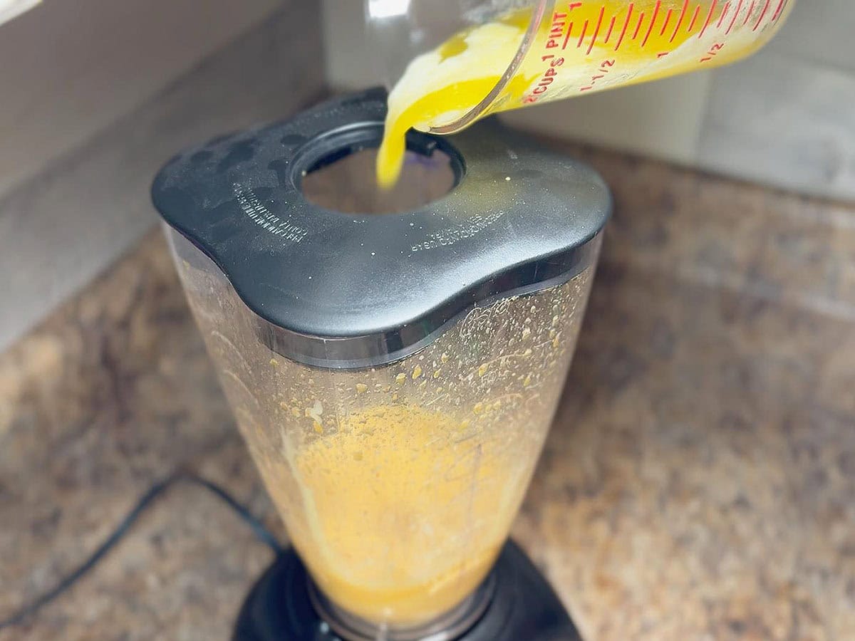 Adding melted butter to the egg mixture while the blender is running.