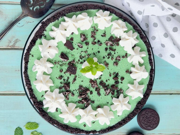 Grasshopper pie decorated with piped whipped cream, crushed cookies and a mint sprig.