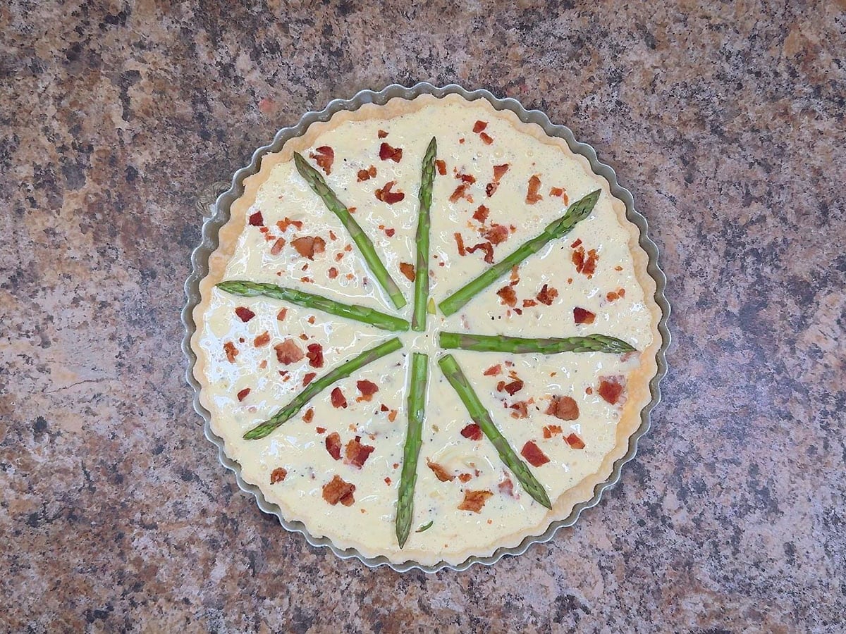 Fresh asparagus stems arranged on top of the egg mixture in the pie shell.
