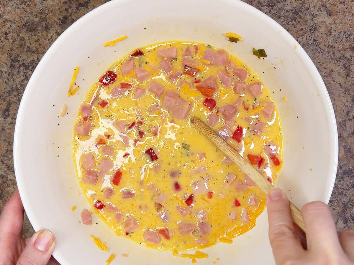 Mixing together the eggs with the ham and the veggies.