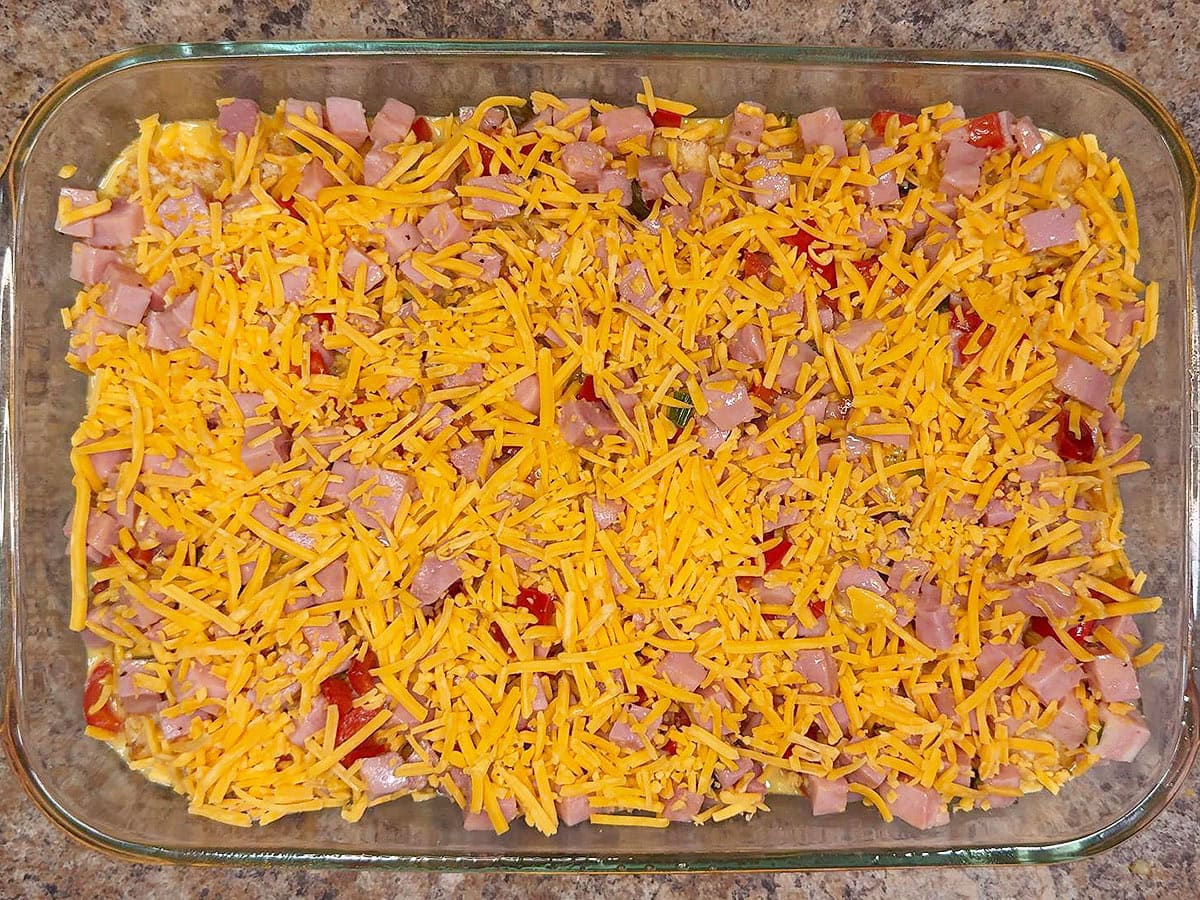 Prepared unbaked casserole topped with shredded cheese.