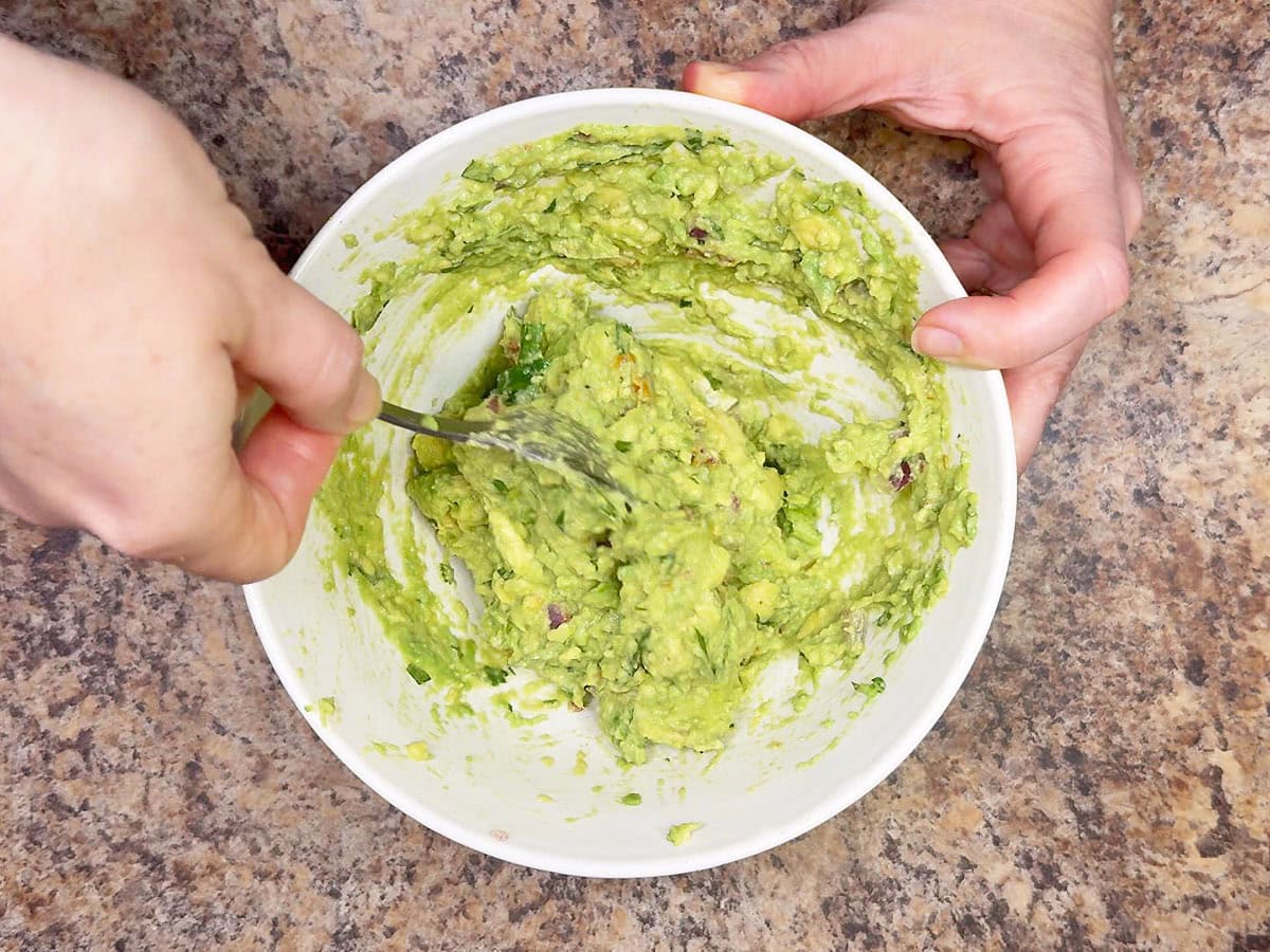 Mashing the guacamole ingredients together.