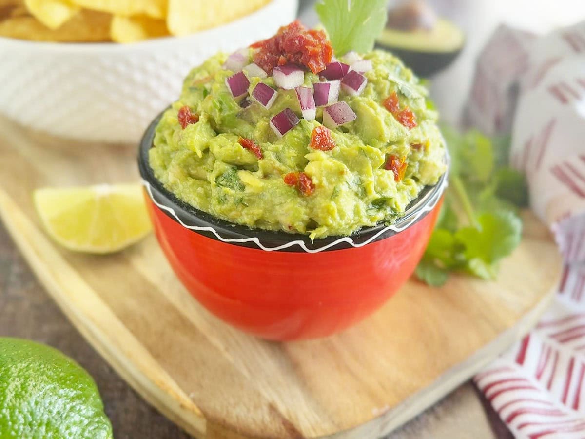 Finished chunky guacamole in a small dish served with tortilla chips.