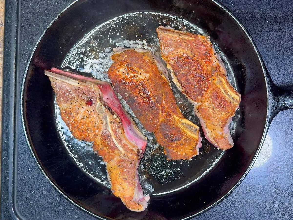 Browning the outside of the pork ribs in a cast iron skillet.