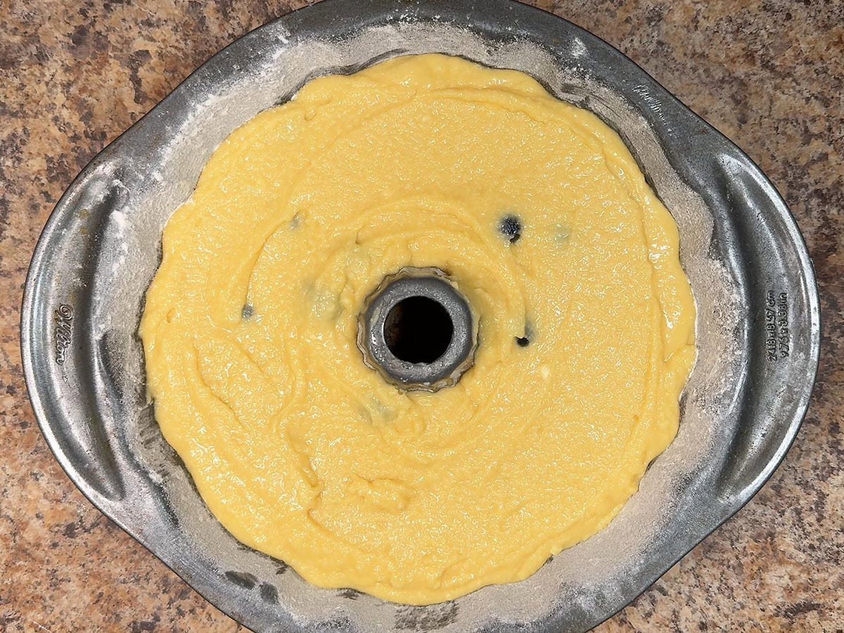 Blueberry pound cake batter spread into a Bundt cake pan.