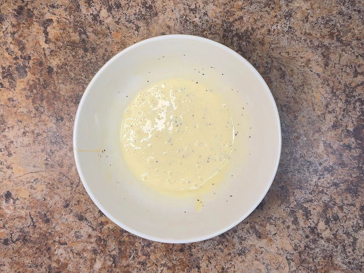 Apple and cabbage slaw dressing ingredients in a small mixing bowl.