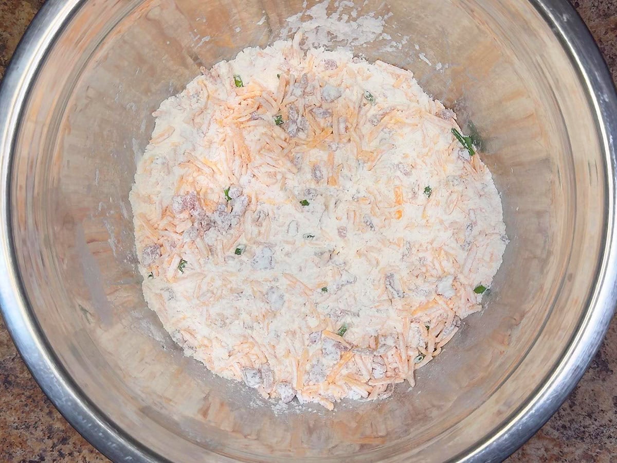 Dry ingredients for bacon and cheese muffins mixed together in a mixing bowl.