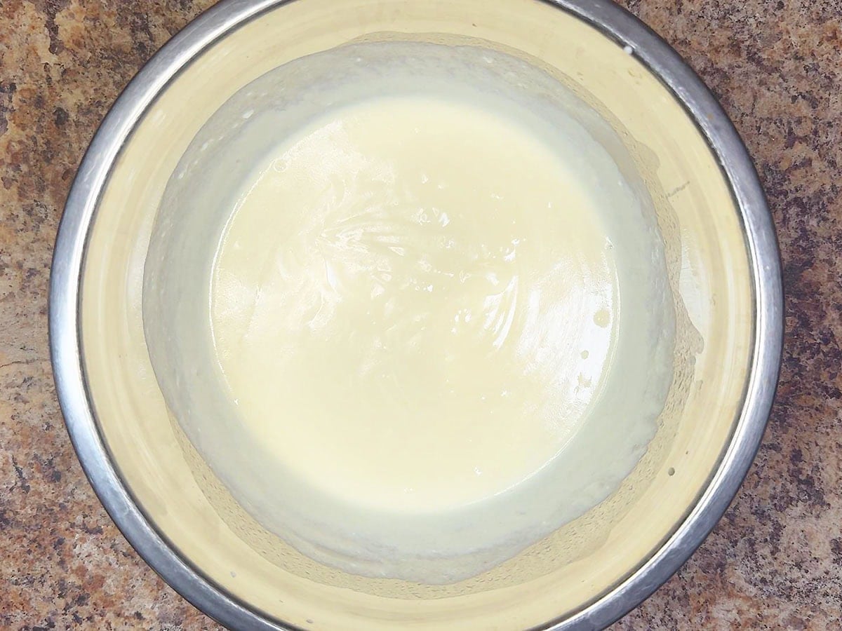 Wet ingredients for bacon and cheese muffins whisked together in a mixing bowl.