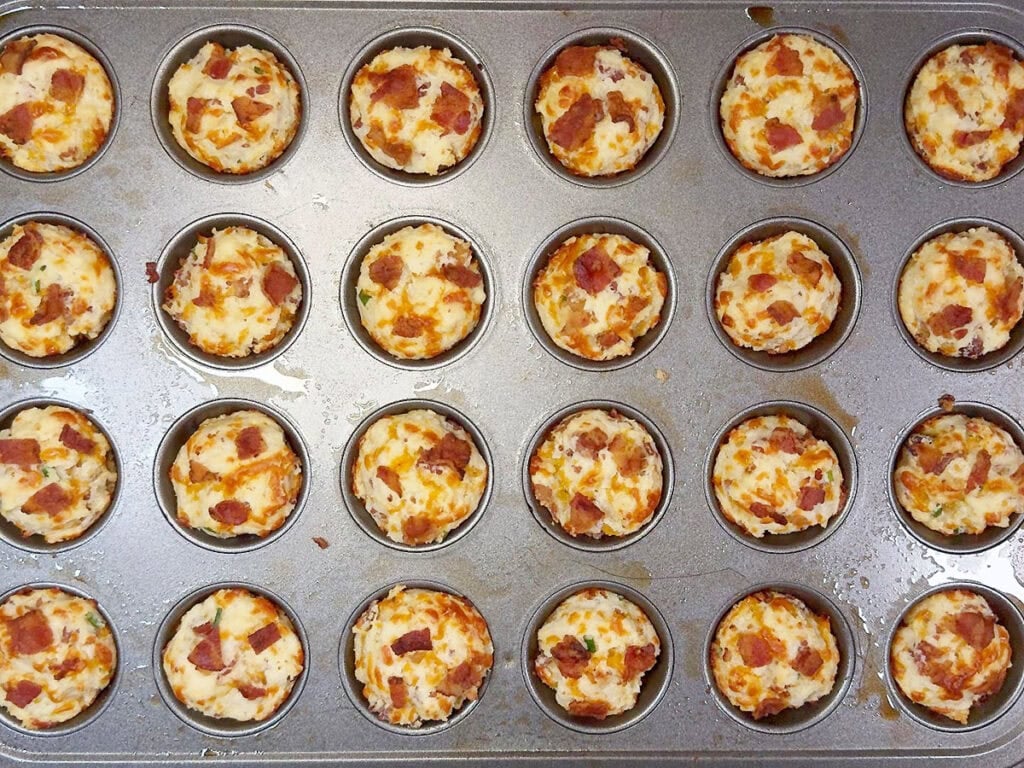 Baked bacon and cheddar muffins cooling in a mini muffin tin.