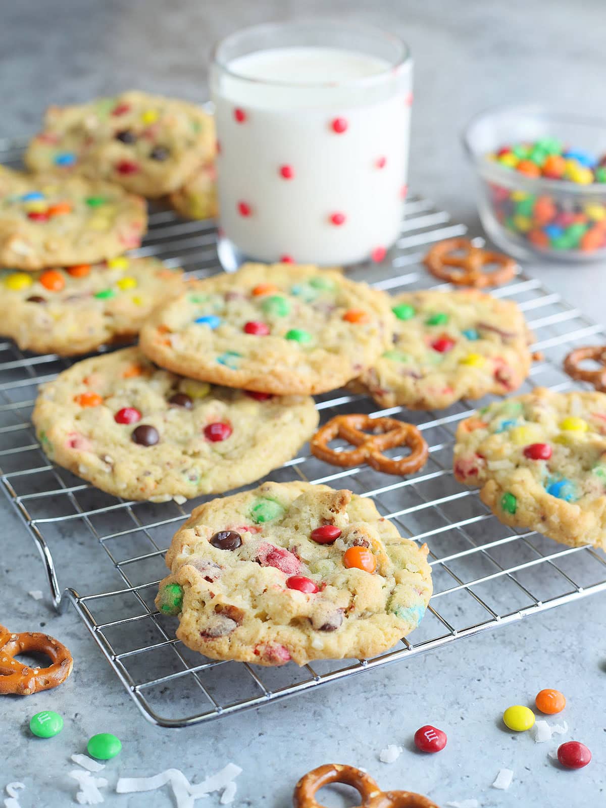 Baked loaded pretzel cookies on a cooking rack with a glass of milk.