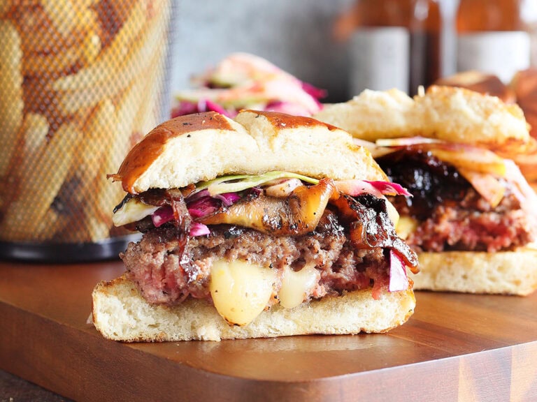 Pepper jack stuffed hamburger sliced in half with melted pepper jack cheese oozing out of the center.