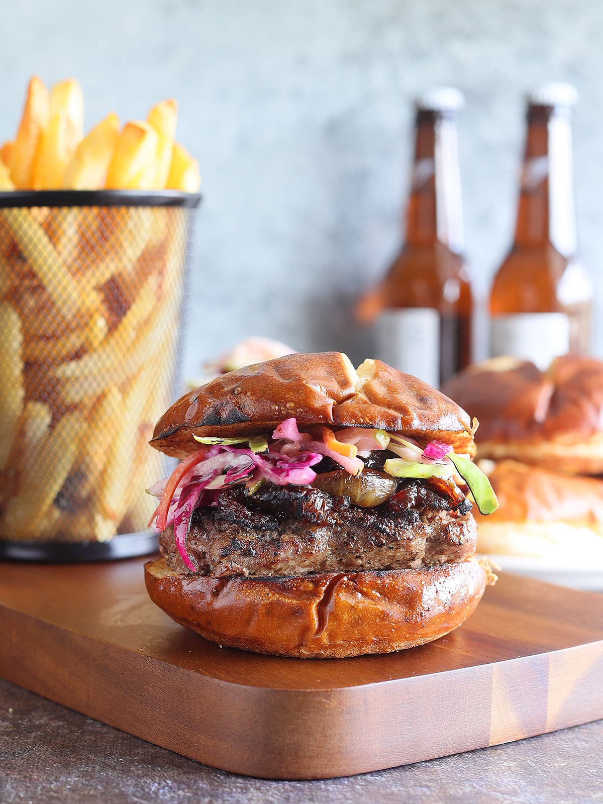 Pepper jack stuffed hamburger garnished with caramelized onions and colslaw on a pretzel roll.