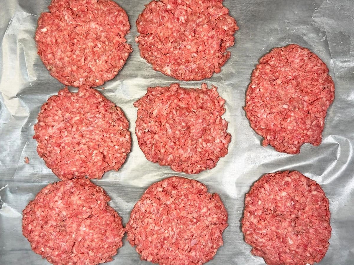Ground beef divided into eight portions and flattened into thin patties.