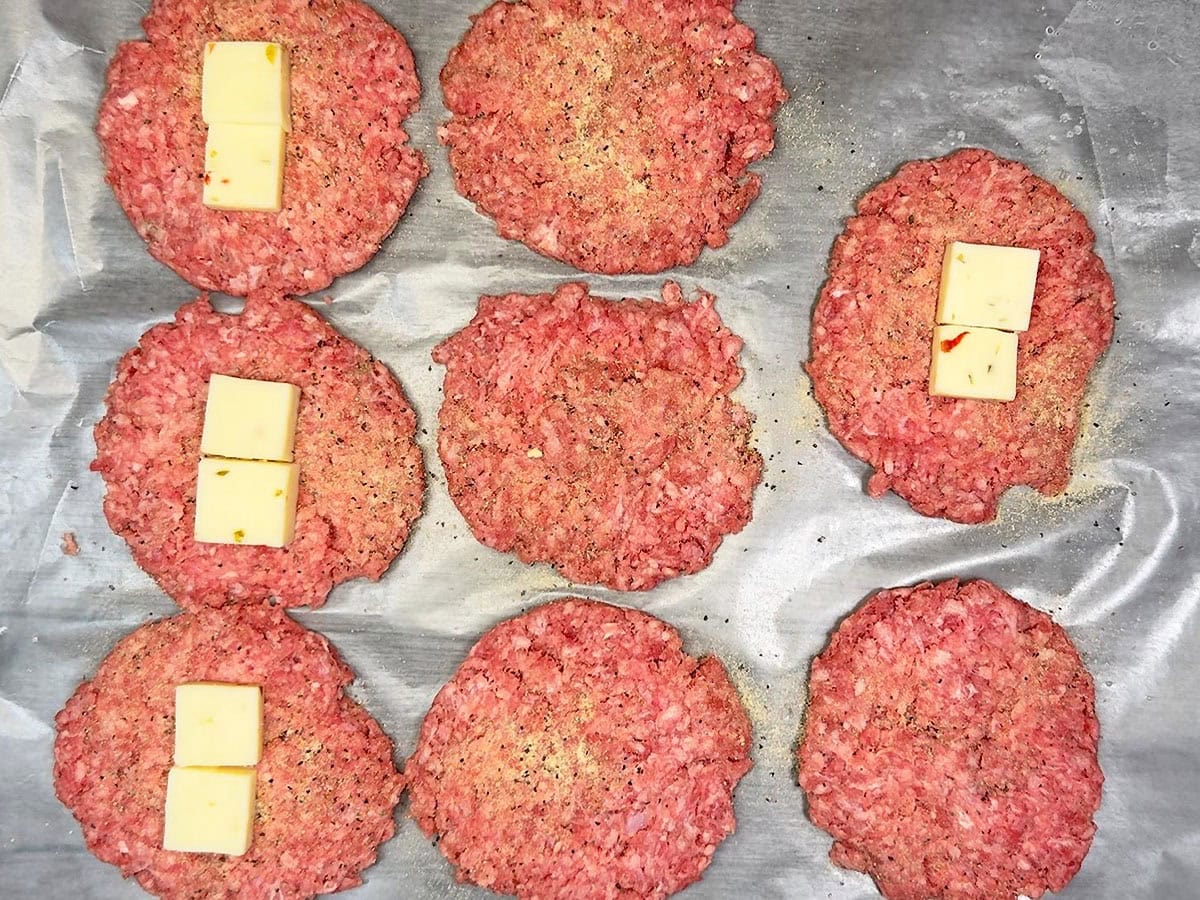 Placing cubes of pepper jack cheese into the center of each patty.