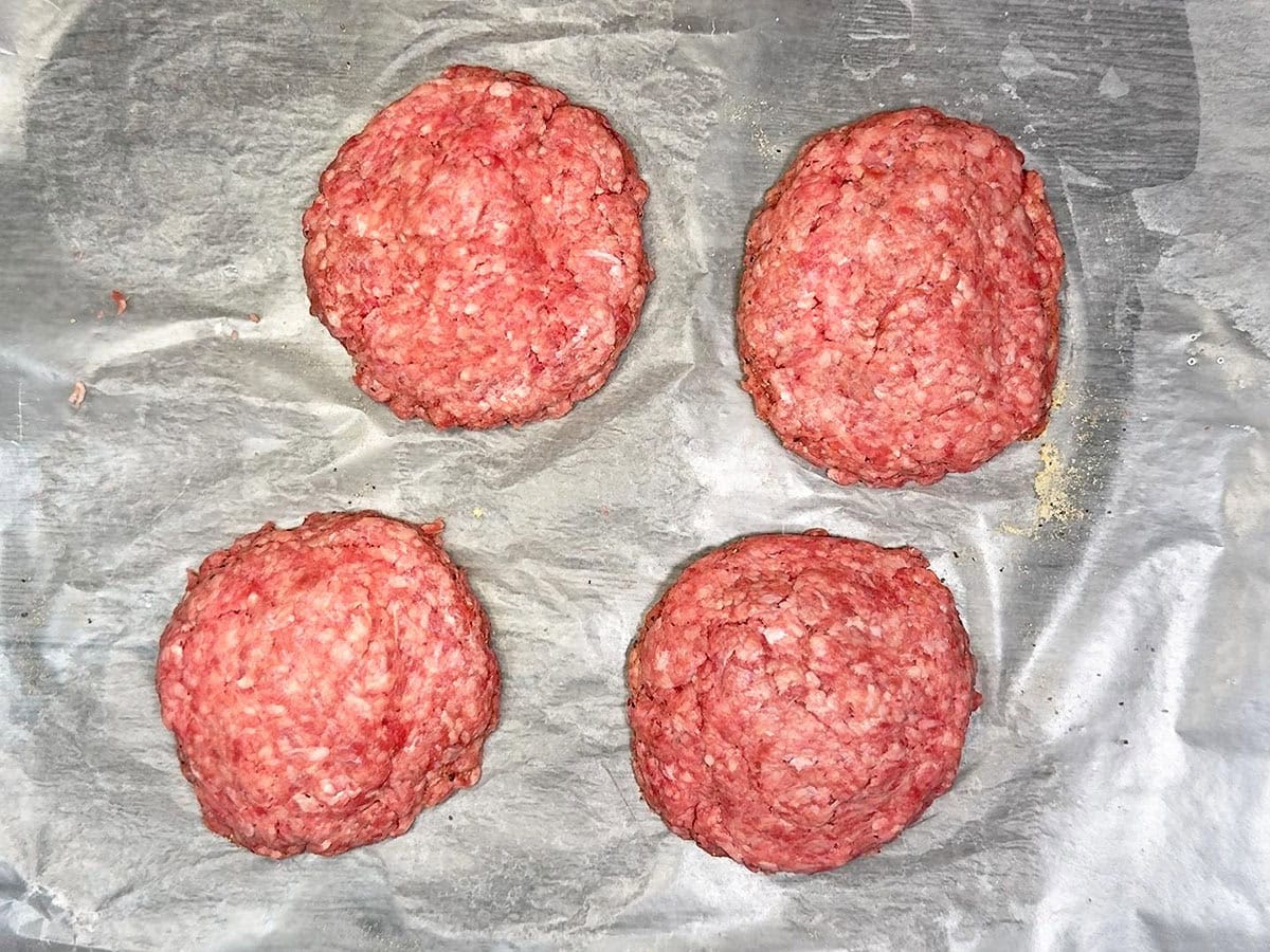 Placing a second patty on top of the cheese and sealing the burger edges.