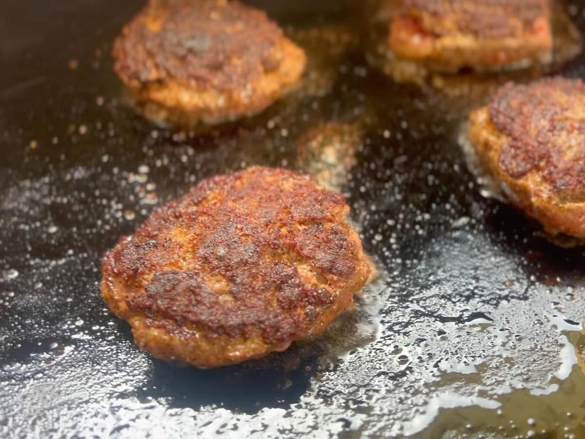Grilling the burger patties until seared and cooked through.