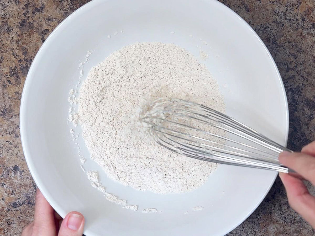 Whisking together flour, baking soda, salt, and cinnamon.