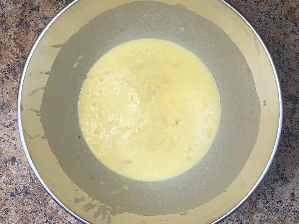 Melted butter, sugar, eggs, vanilla, mashed bananas, and sour cream mixed together in a large mixing bowl.