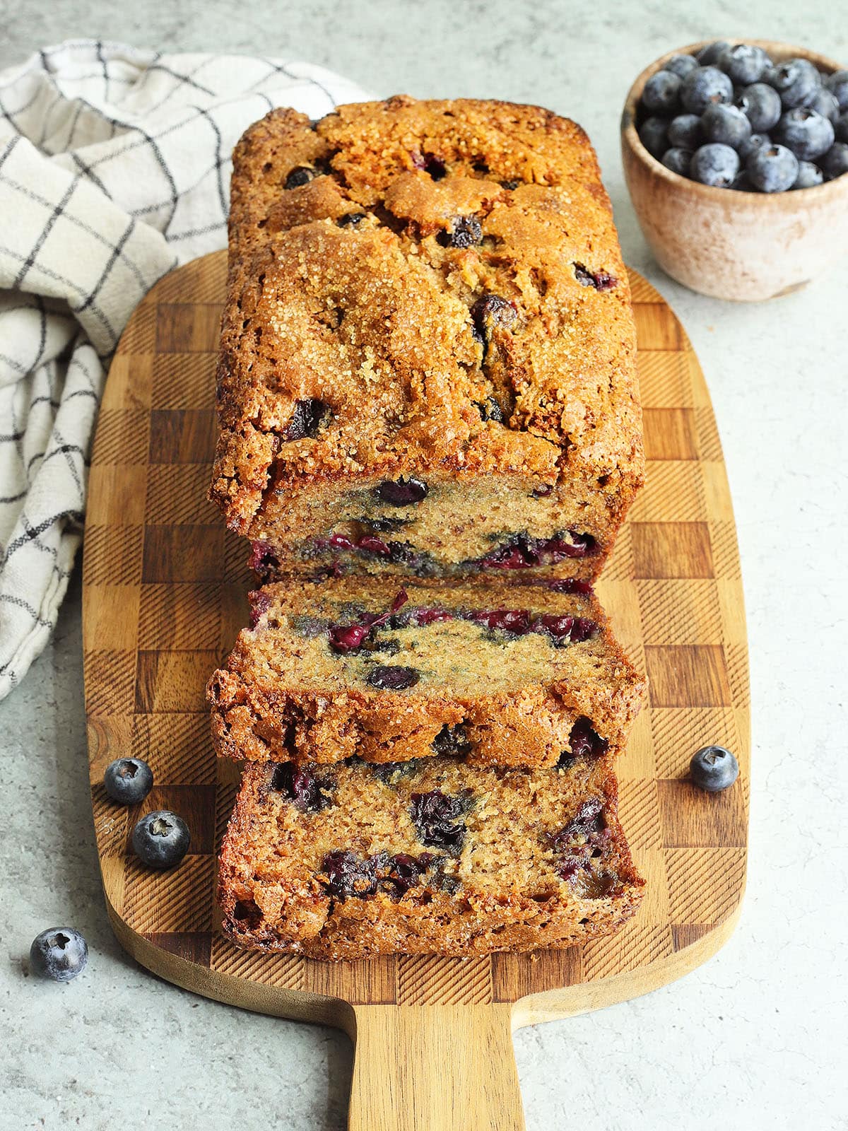 Sliced blueberry banana bread on a wooden cutting board.