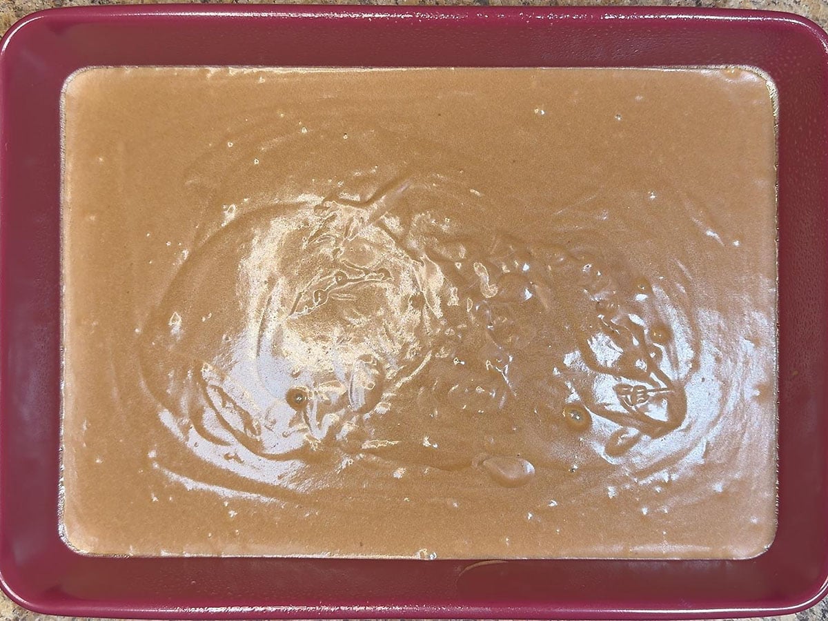 Cake batter poured into a greased cake pan.
