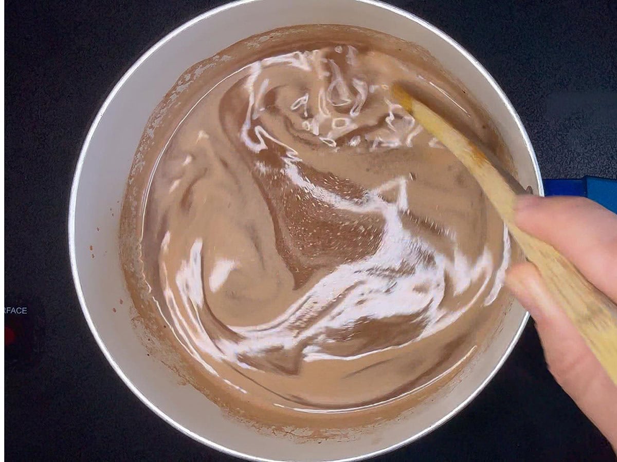 Stirring the butter, Coca-Cola, and cocoa together in a medium saucepan.