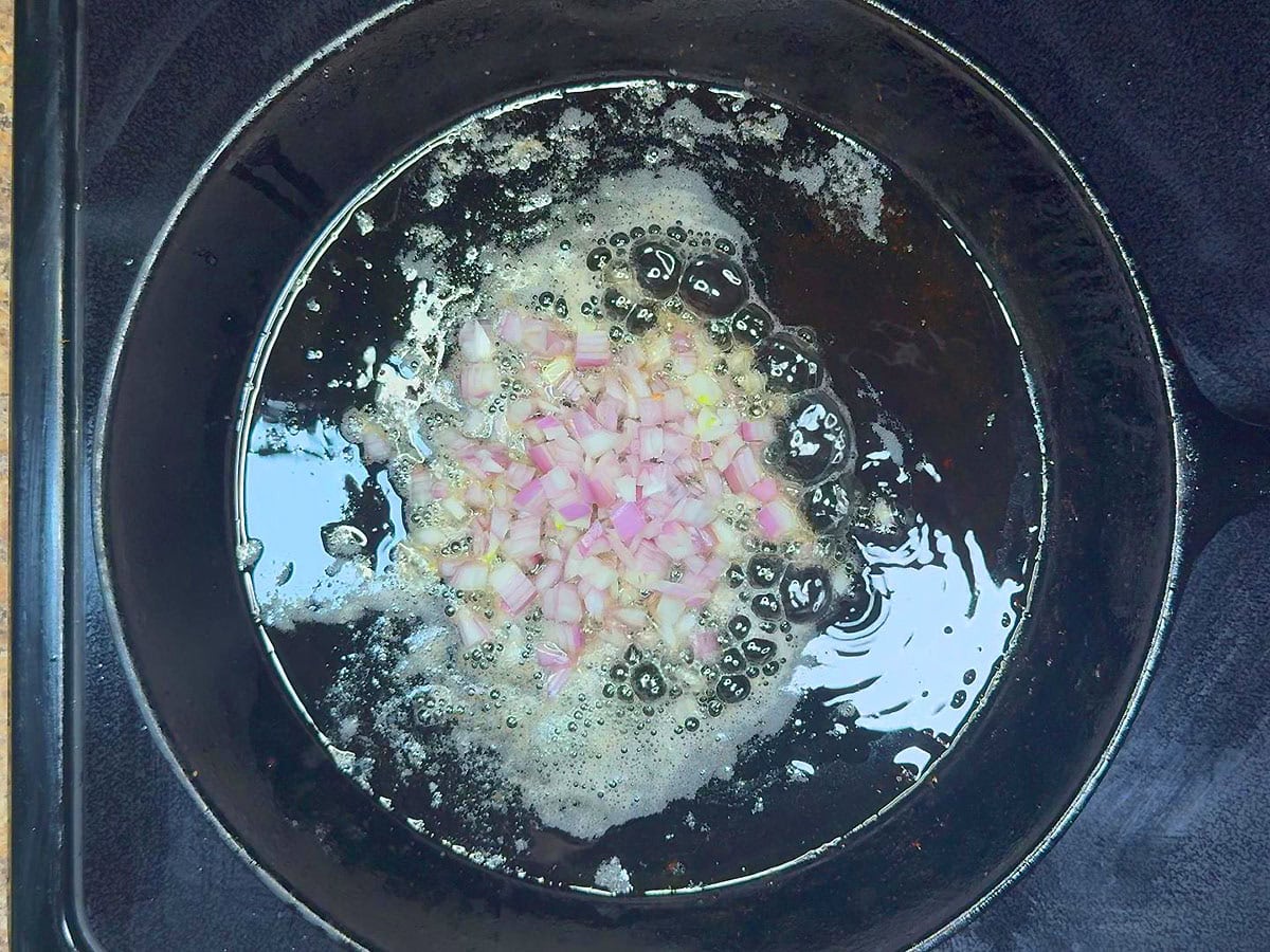 Cooking diced shallots in the rendered bacon fat.