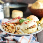 Country eggs benedict on a plate with a side of hash brown potatoes and bacon.