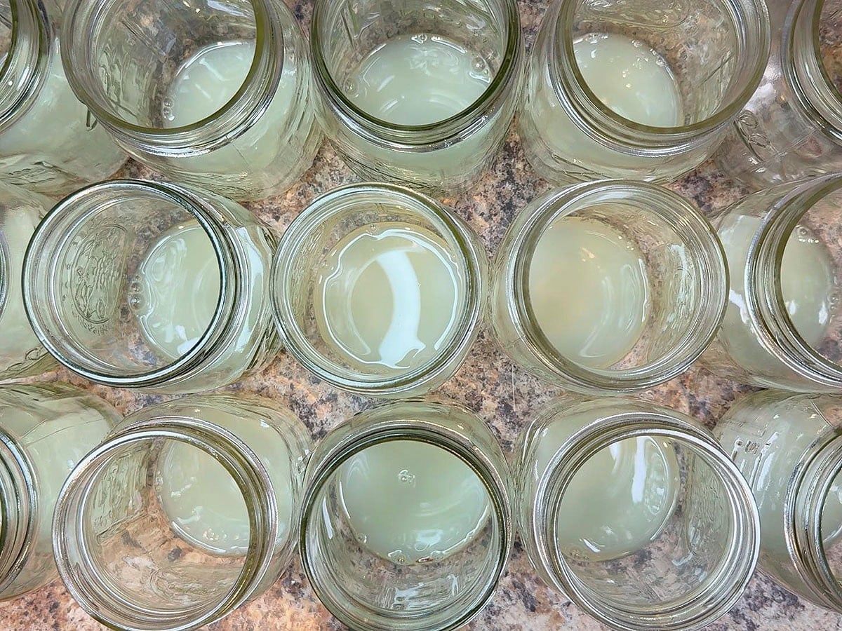 Glass mason jars with lemon juice added to the bottom.