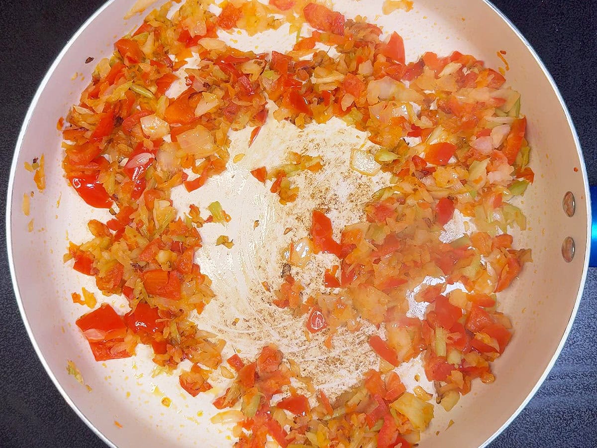 Sauteed red bell pepper, onion, and celery in a large skillet.