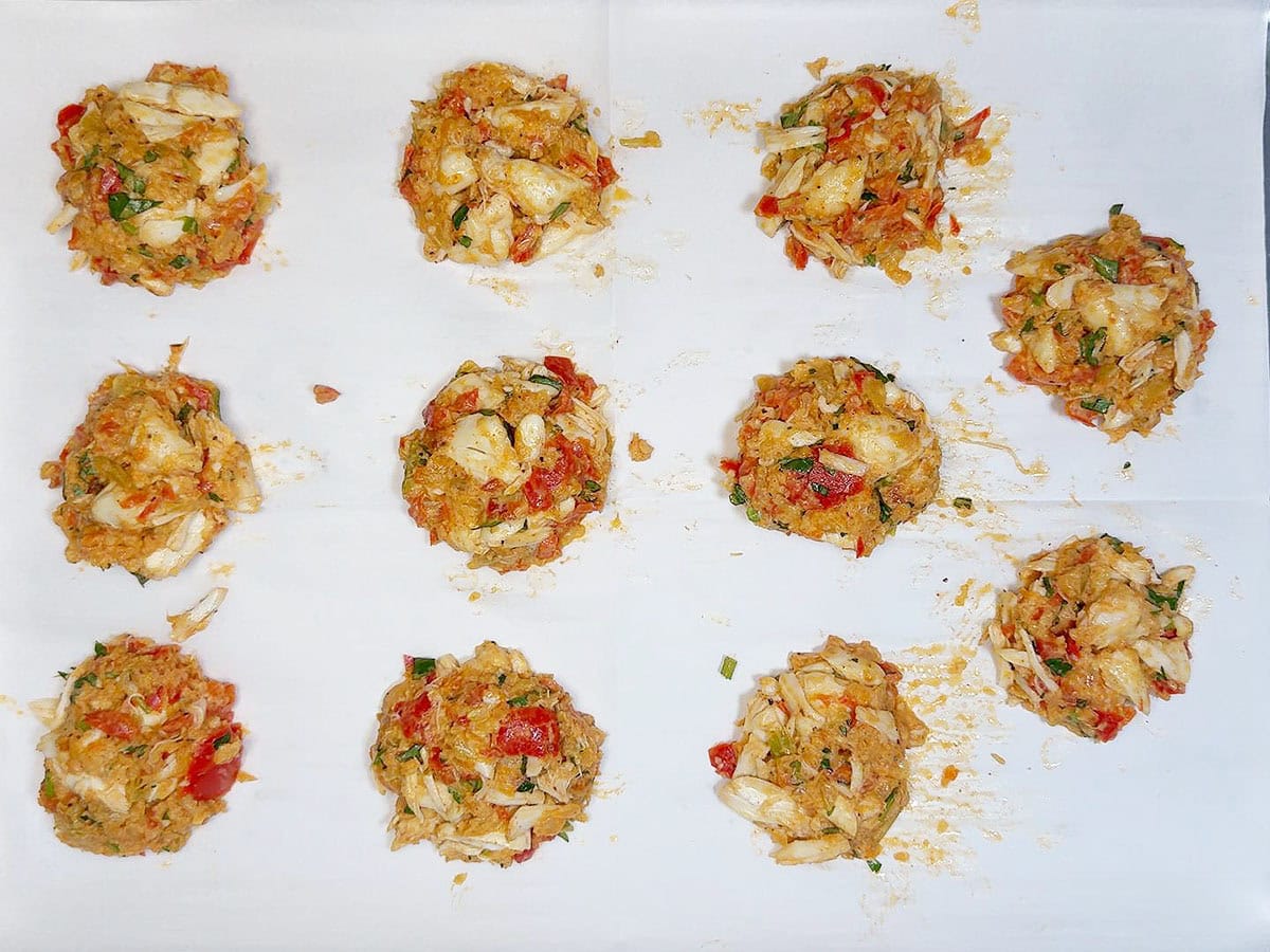 Crab mixture formed into patties on a parchment paper lined baking sheet.